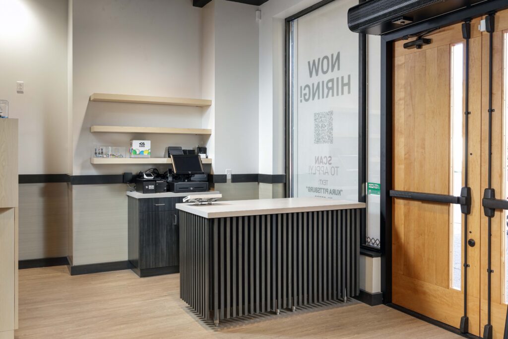 A service counter in a lobby with a “Now Hiring” sign on the window.