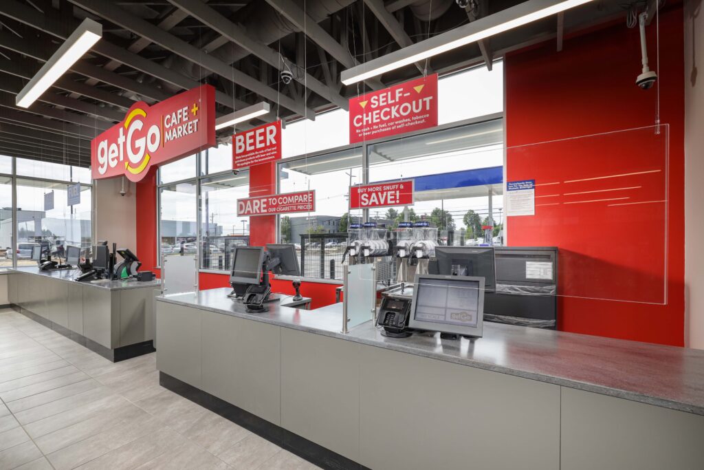 Checkout counter at a GetGo cafe and market with signage for self-checkout, beer, and cigarette pricing.