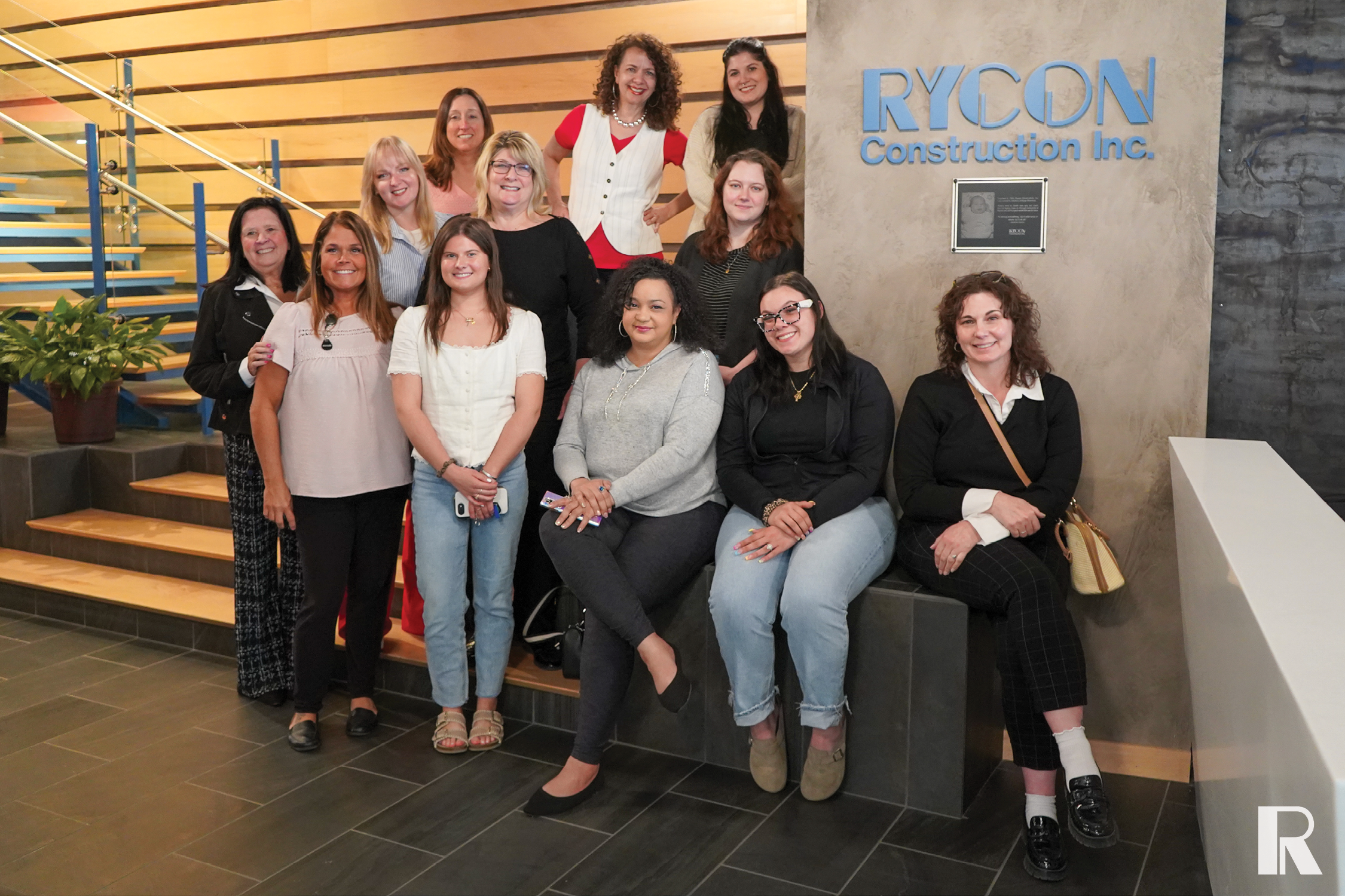 A group of thirteen women posing for a photo in the lobby of Rycon Construction Inc.