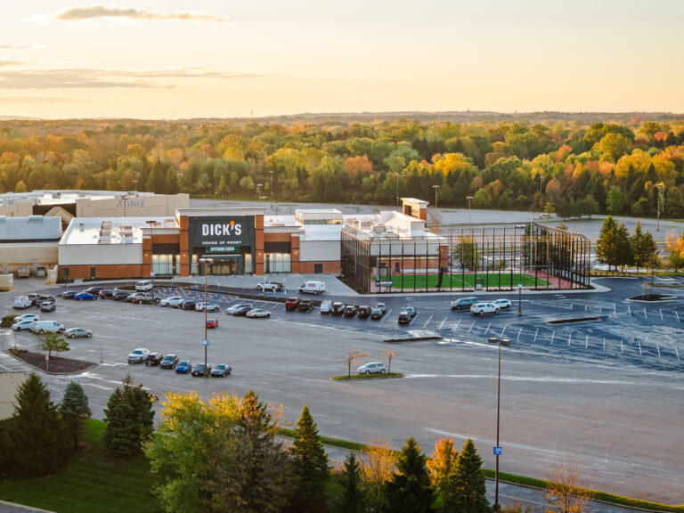 Aerial view of a Dick’s House of Sport store with an outdoor athletic field in a large parking lot surrounded by autumn trees.