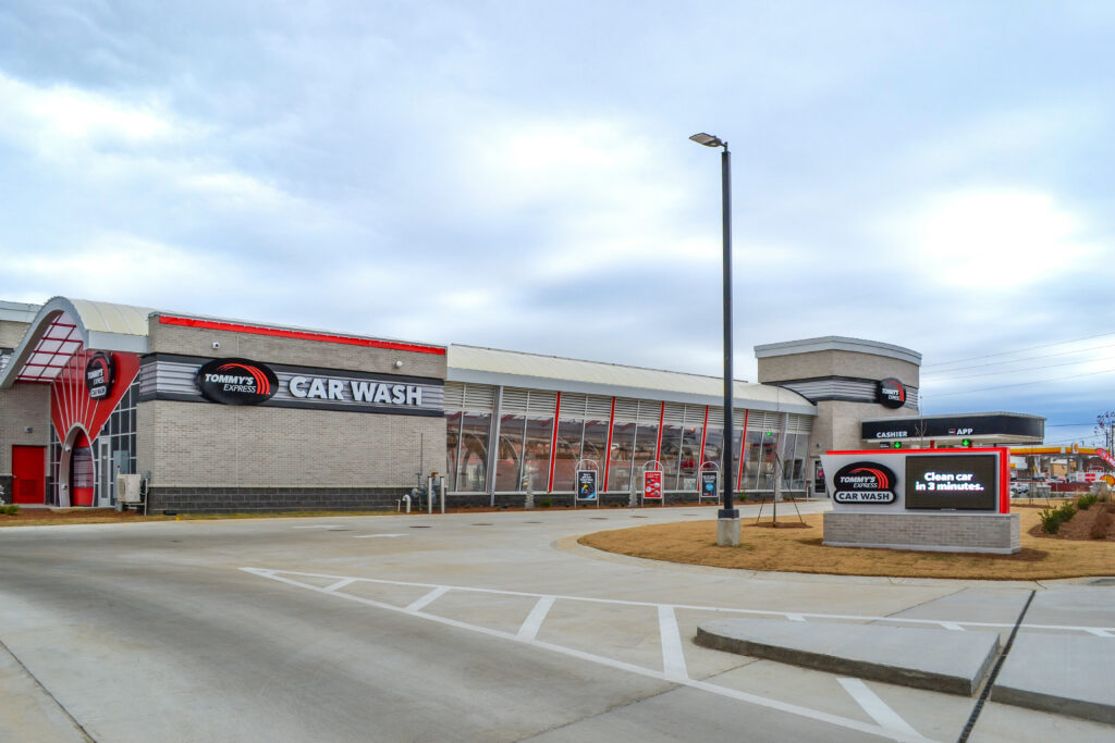 A Tommy’s Express Car Wash building with a digital sign that reads “Clean car in 3 minutes.”