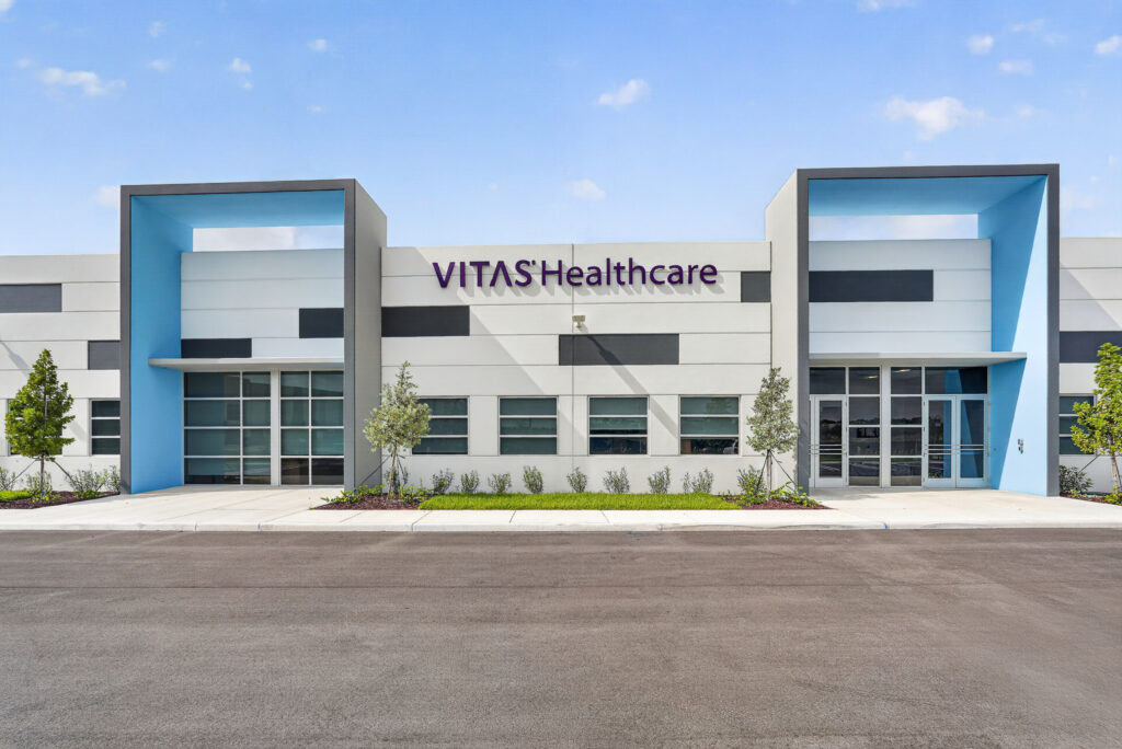 Exterior view of a VITAS Healthcare building with modern gray, white, and blue paneling.