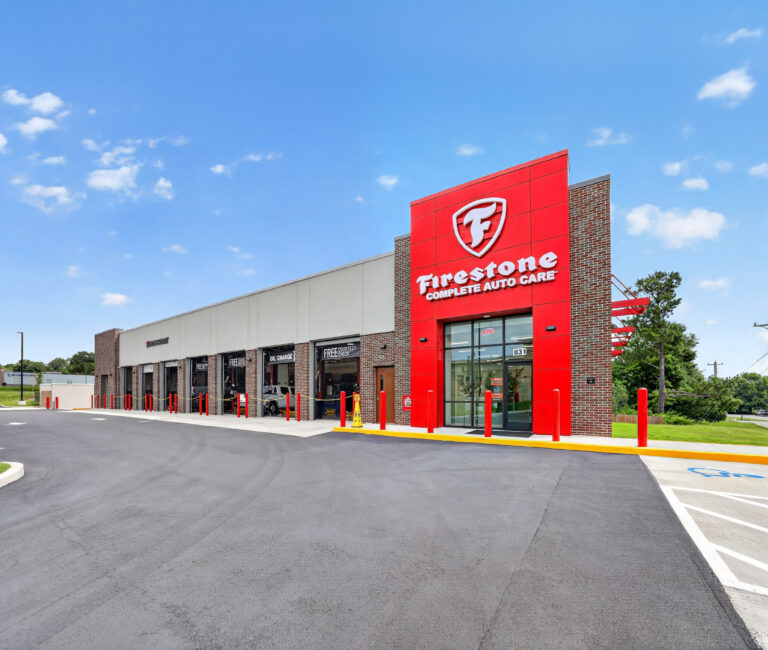 Firestone Complete Auto Care center exterior with service bays under a blue sky.