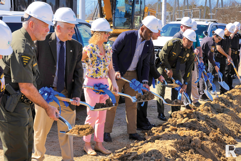 A group of people wearing hard hats and holding ceremonial shovels at a ground-breaking ceremony.