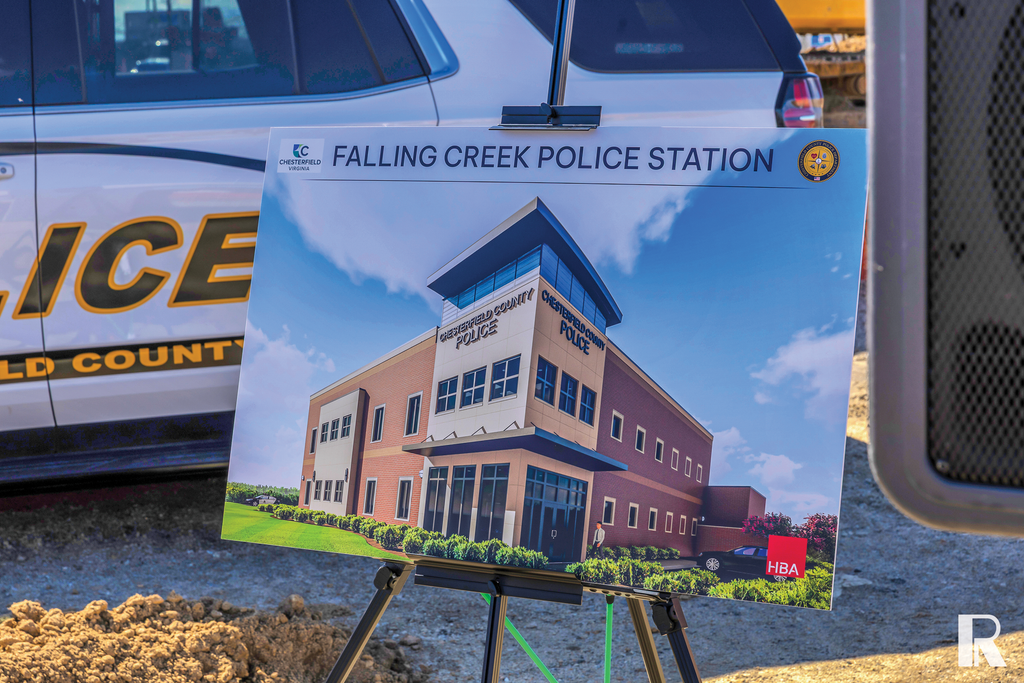 An architectural rendering of the Falling Creek Police Station on a display board in front of a police vehicle.