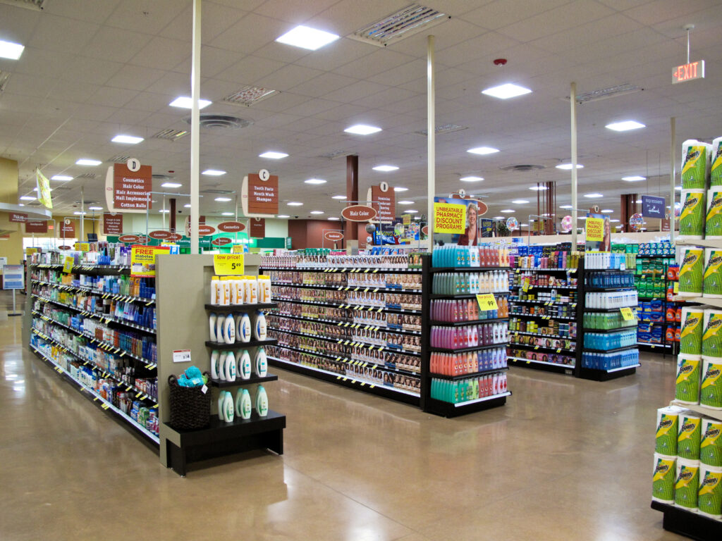 Aisle view inside a retail pharmacy with shelves stocked with personal care and beauty products.