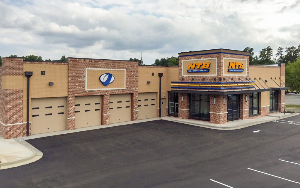 An NTB Tire & Service Center with a brick exterior, multiple service bays, and a paved parking lot.