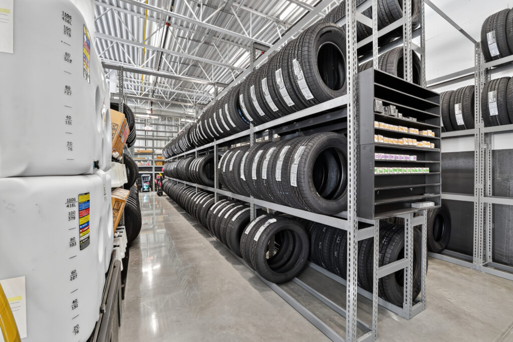 Rows of tires stacked on industrial metal shelving in a warehouse.