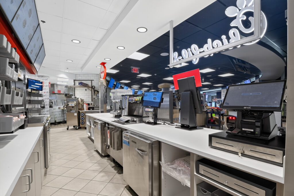 Interior of a Chick-fil-A service counter featuring point-of-sale registers, drink dispensers, and stainless steel equipment.