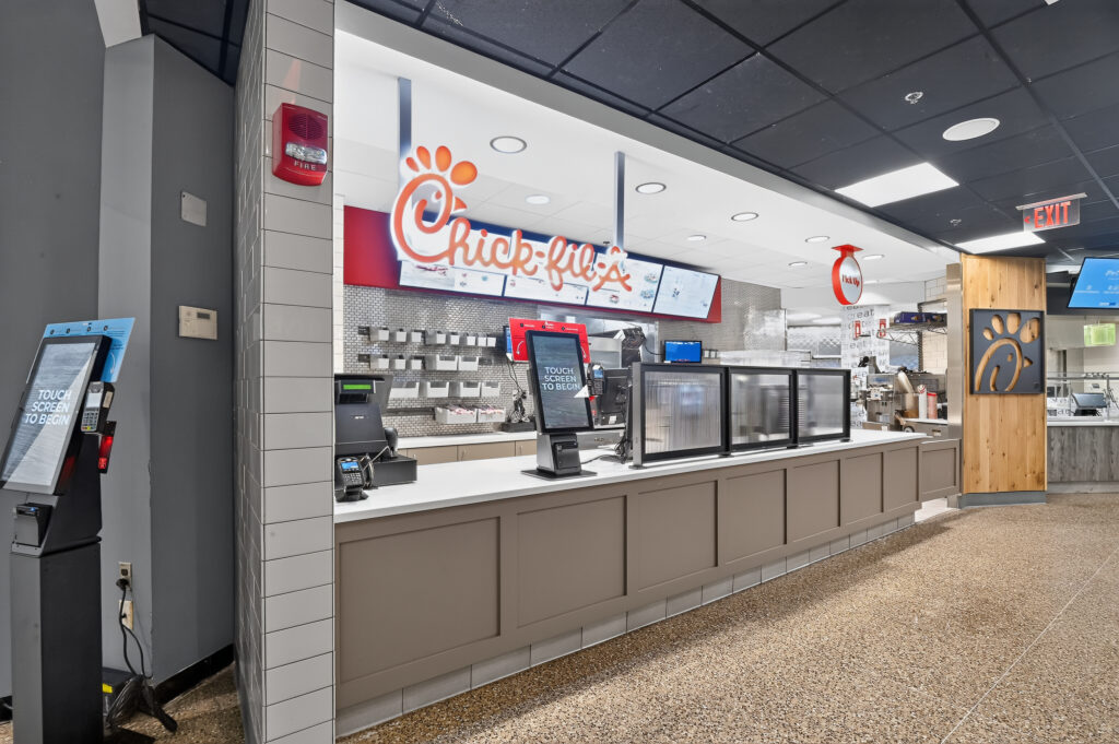 Chick-fil-A service counter with a self-service ordering kiosk in the foreground.