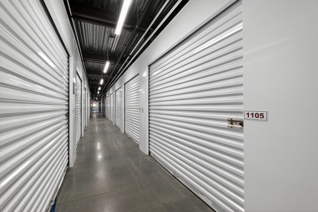 A hallway of white, corrugated metal self-storage units with unit 1105 in the foreground.