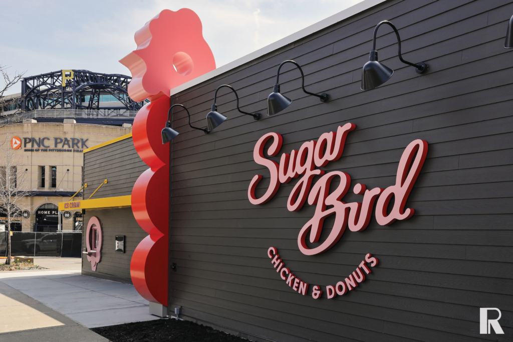 Exterior wall of Sugar Bird Chicken & Donuts, with PNC Park visible in the background.