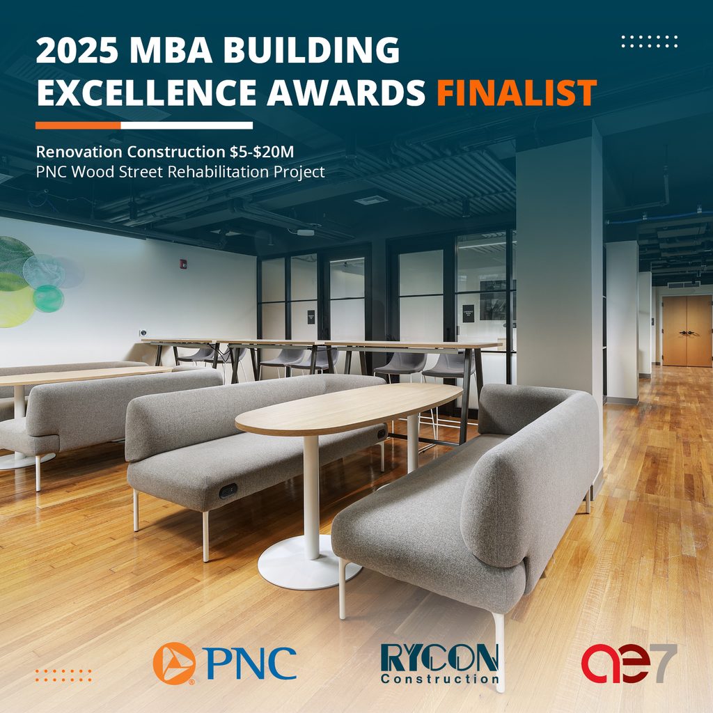 Text overlay reads: “2025 MBA Building Excellence Awards Finalist, Renovation Construction $5-$20M, PNC Wood Street Rehabilitation Project.” Below, the lobby features grey sofas and tables on a hardwood floor.