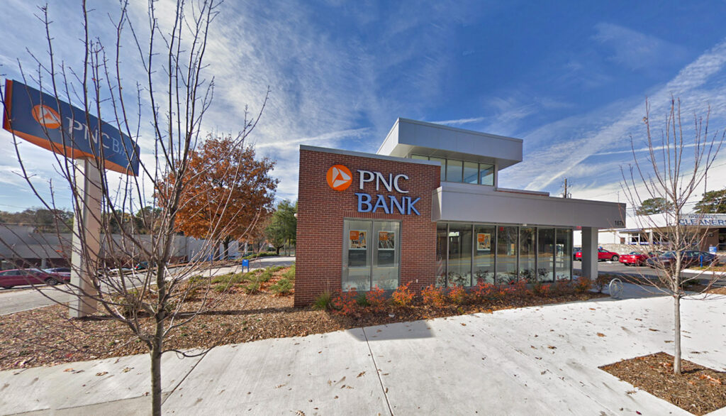 A PNC Bank branch with a brick exterior and a free-standing sign in a parking lot.