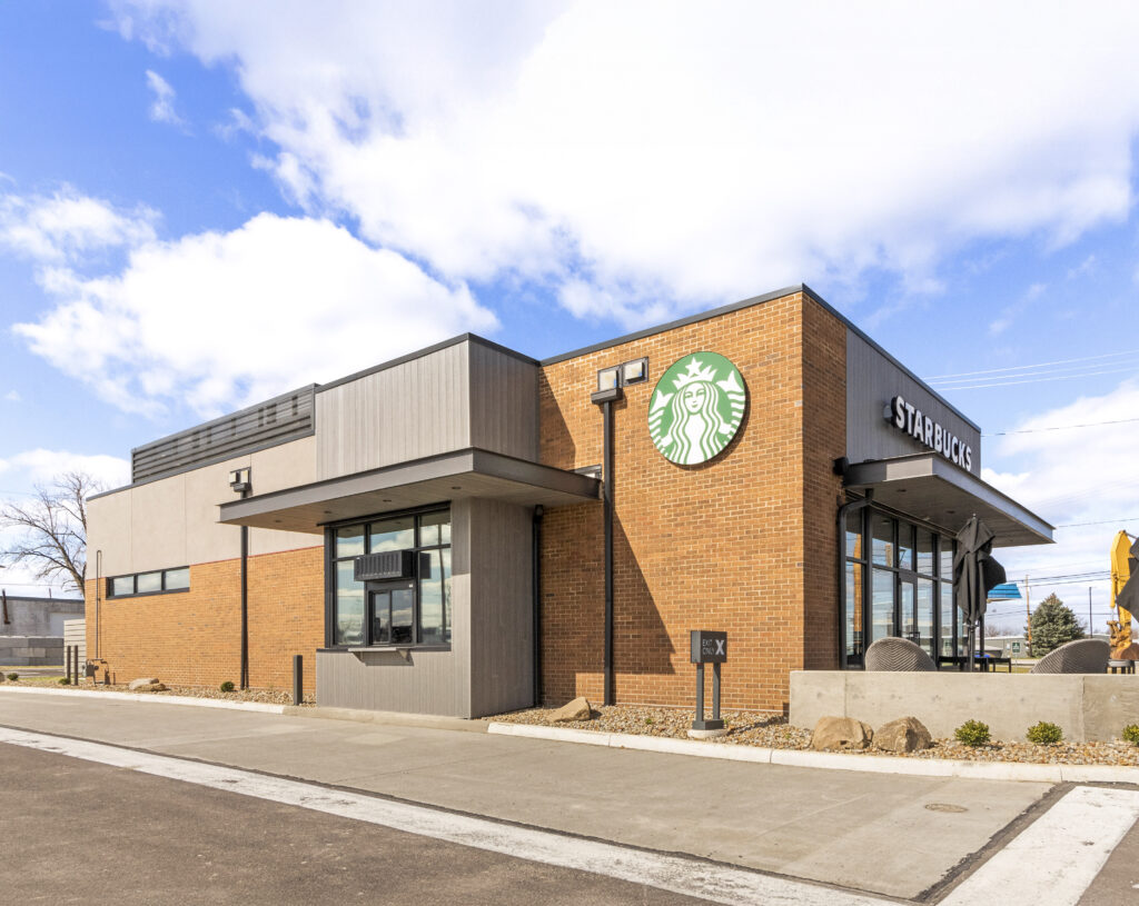 A Starbucks coffee shop with a brick exterior, a drive-thru window, and a large circular green logo sign.