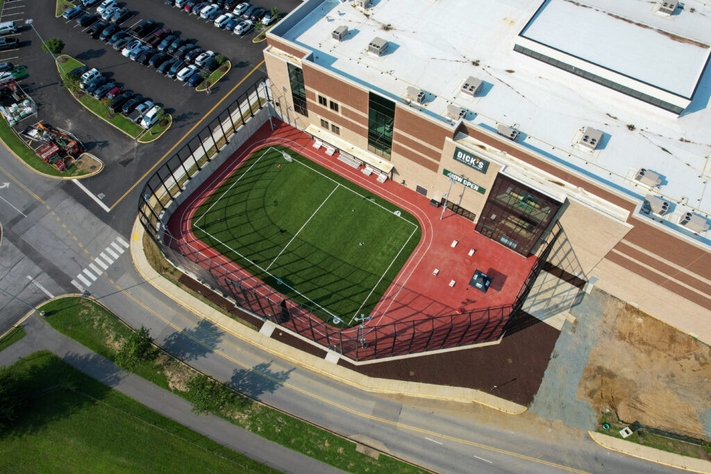 Aerial view of a Dick’s Sporting Goods store with an outdoor turf field and red running track attached to the side of the building.