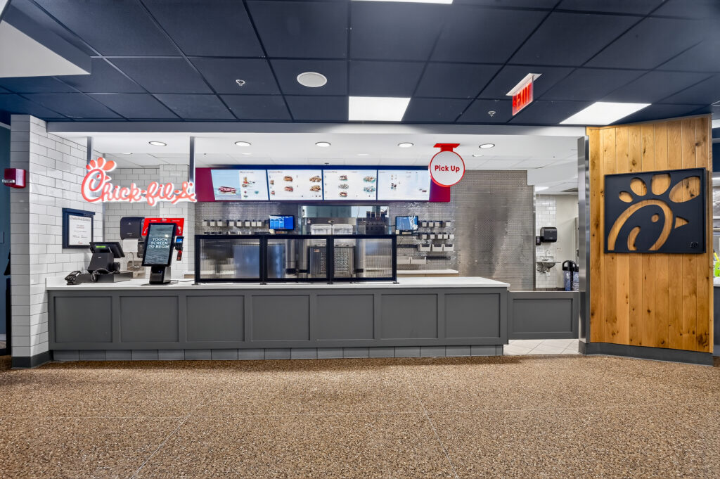 Chick-fil-A service counter with a digital menu board, self-ordering kiosks, and a designated pickup area.
