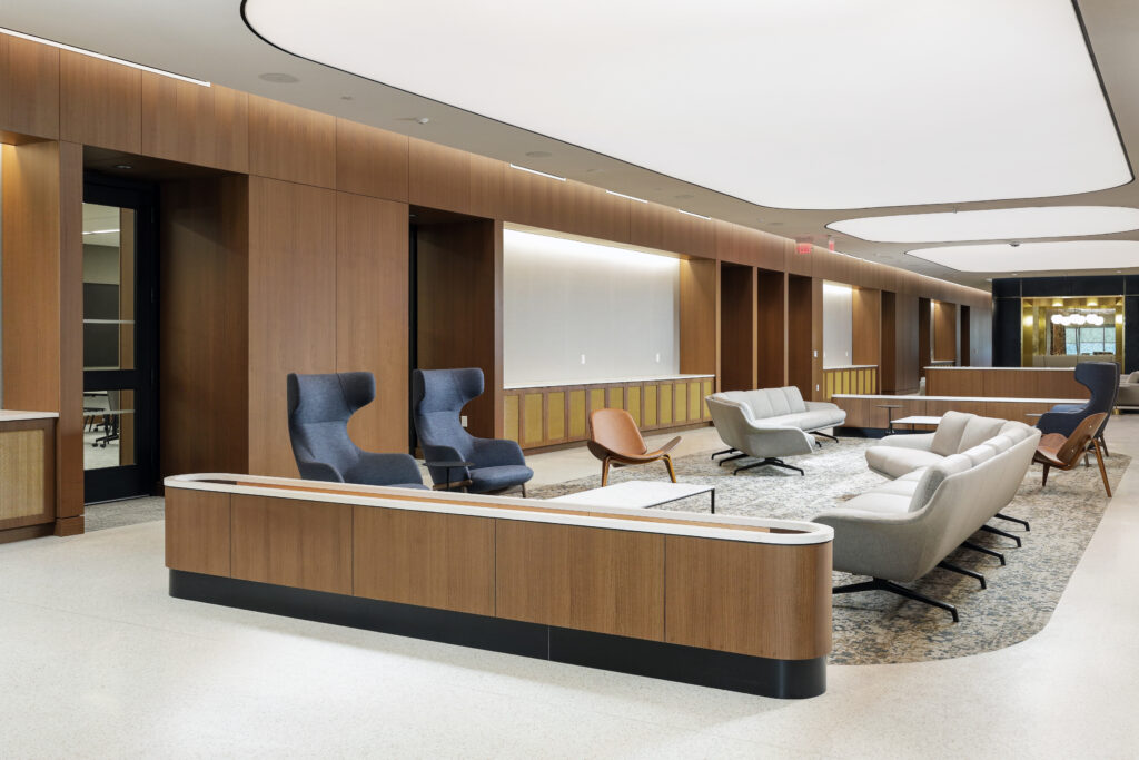 Modern office lobby with wood paneled walls, a large area rug, and groupings of contemporary chairs and sofas.